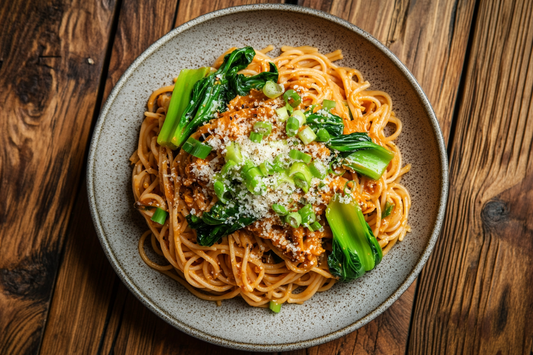 Vegane Ssamjang-Pasta mit Pak Choi, serviert auf einem rustikalen Teller, garniert mit veganem Parmesan und Frühlingszwiebeln
