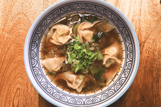 Dampfende Wantan-Suppe mit zarten Dumplings, Pak Choi und Frühlingszwiebeln in einer aromatischen Ingwer-Sojasaucen-Brühe